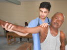 Ashutosh Sharma, a third-year medical student, examines a man who is unable to raise his right arm more than 45 degrees from his hip.